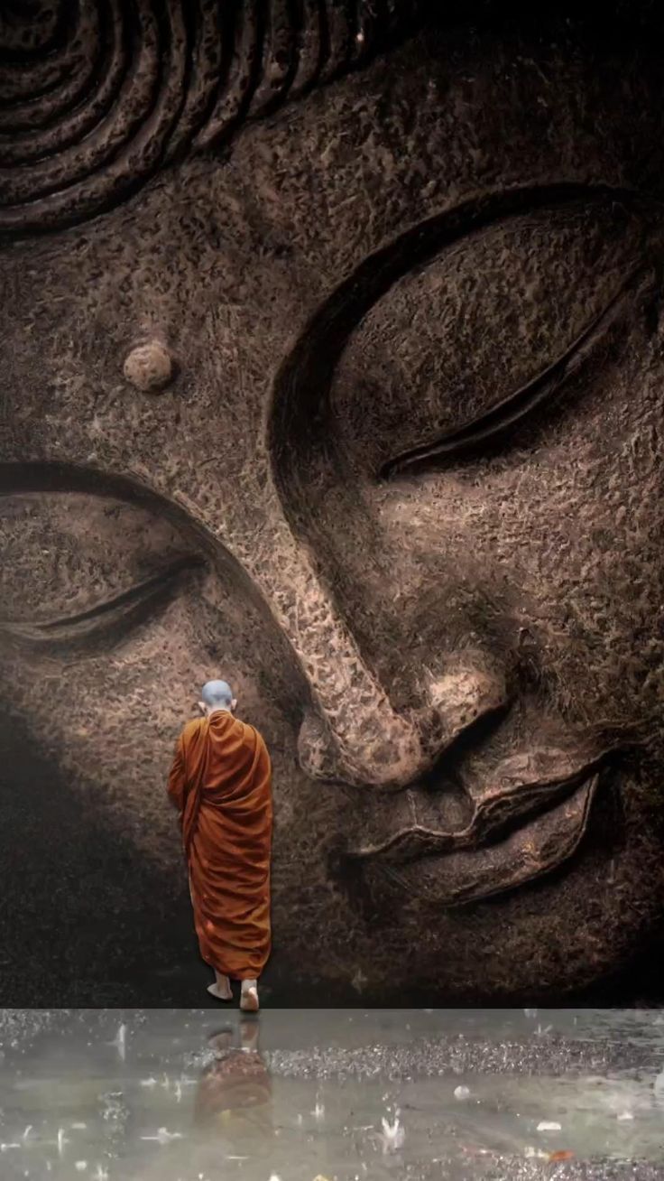 Monk walking before giant Buddha statue.