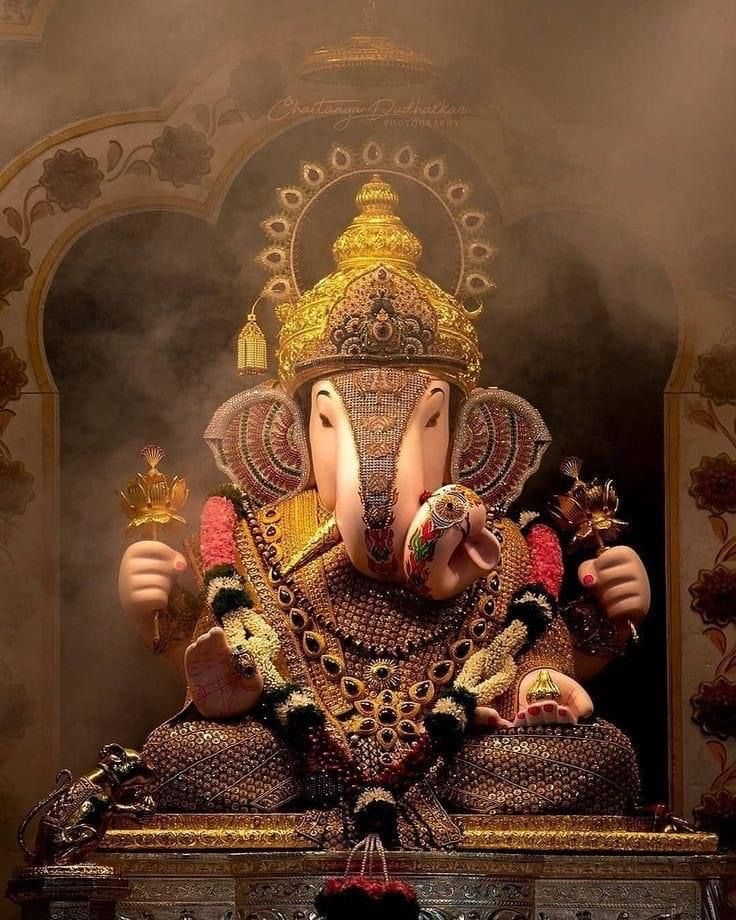 Golden Ganesha statue with mouse and modak.