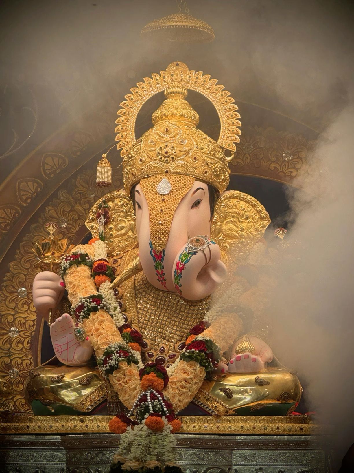 Golden Ganesha idol with floral decorations