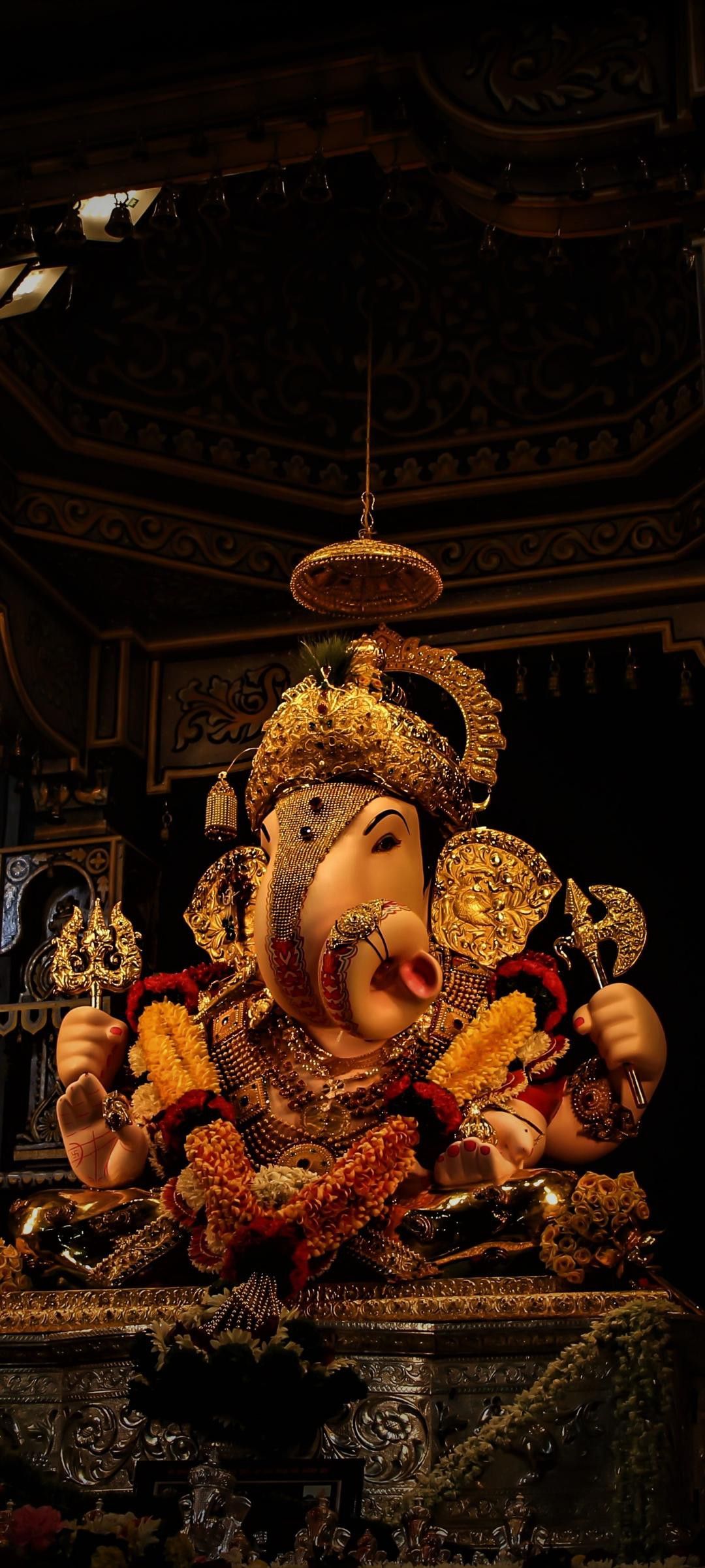 Golden statue of Lord Ganesha adorned with flowers