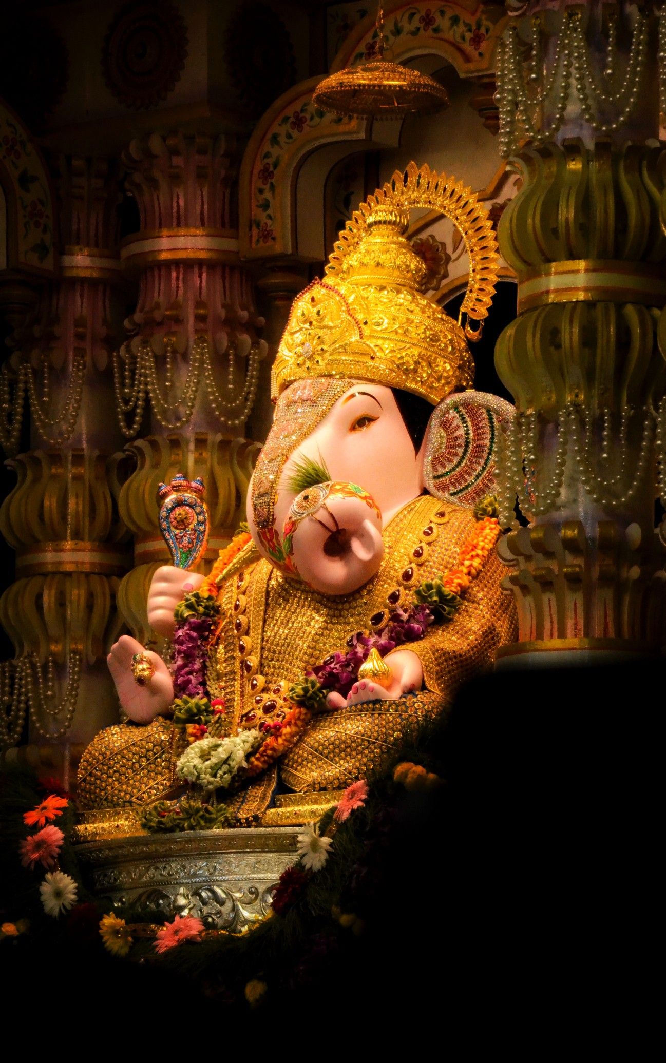 Golden Ganesha idol with floral decorations