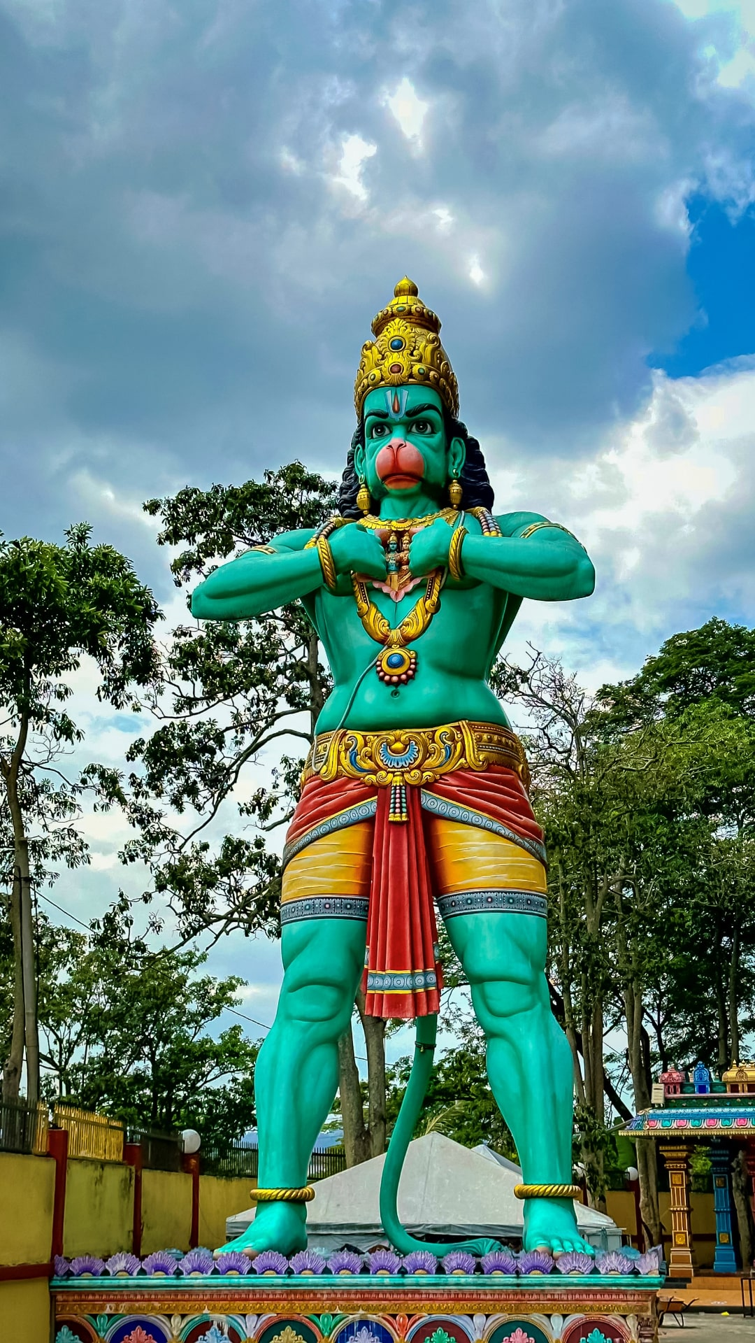 Hanuman statue against a cloudy sky.