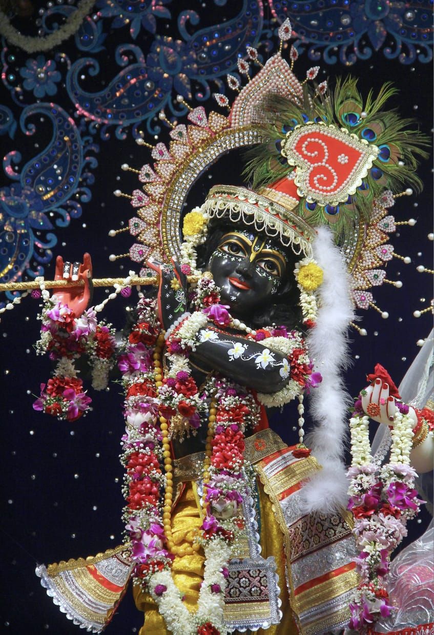 Krishna playing a flute, adorned with flowers