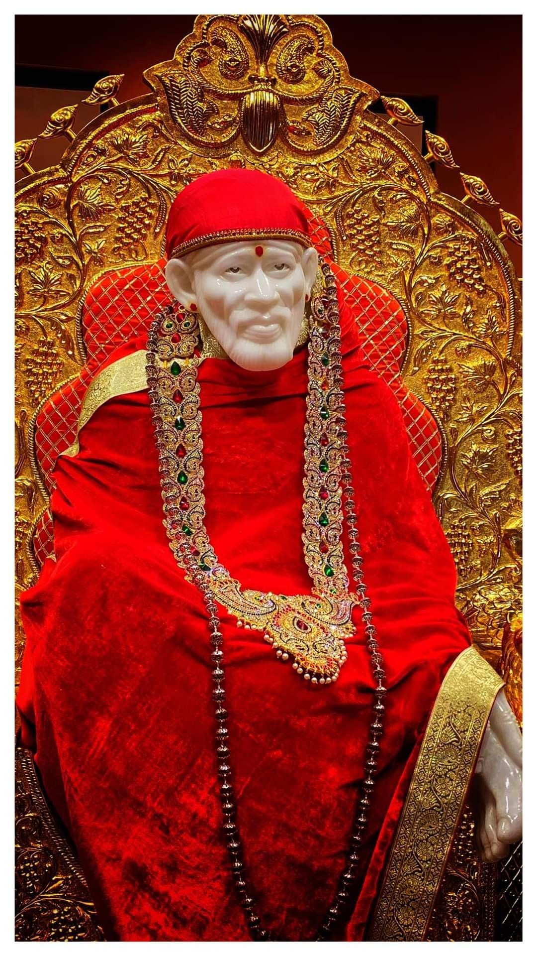 Sai Baba adorned in gold and red