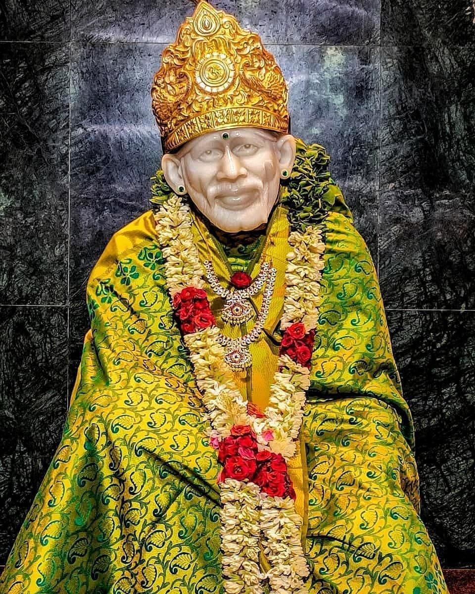 Marble statue of Sai Baba with flowers.