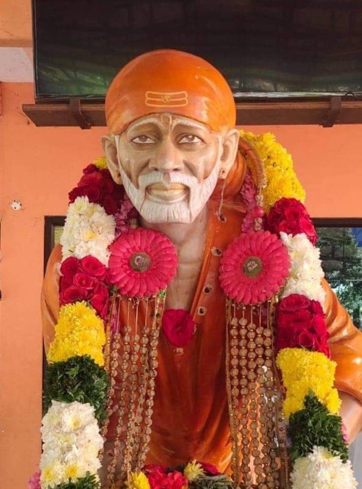 Sai Baba statue adorned with flowers.