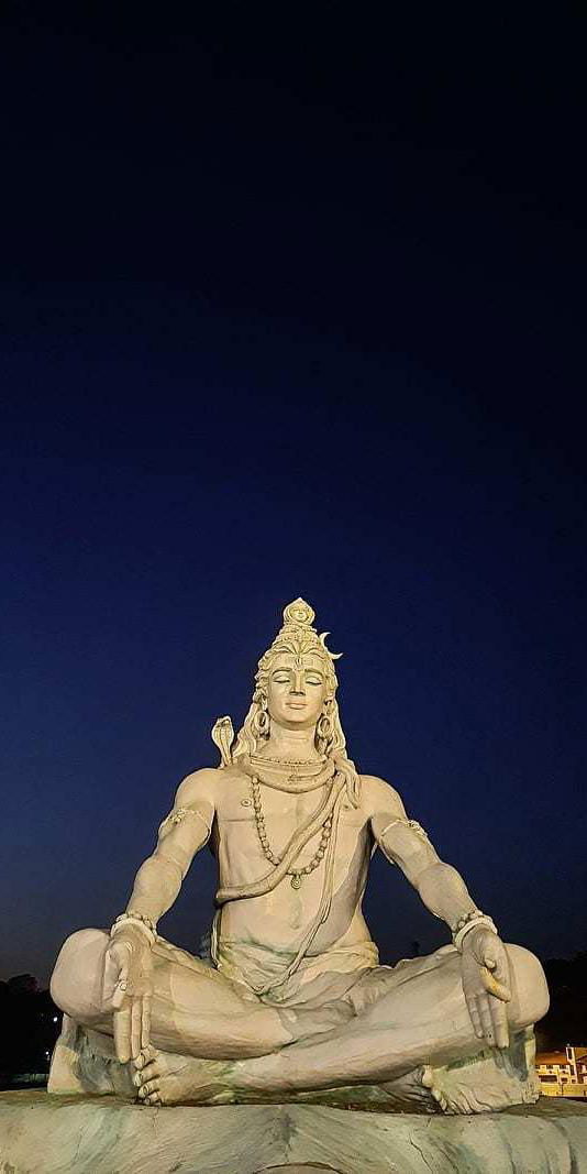 Meditating Shiva statue under night sky