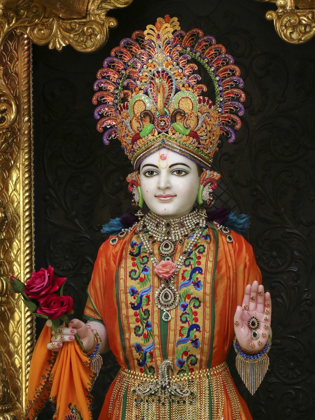 Swaminarayan with floral crown blessing devotees
