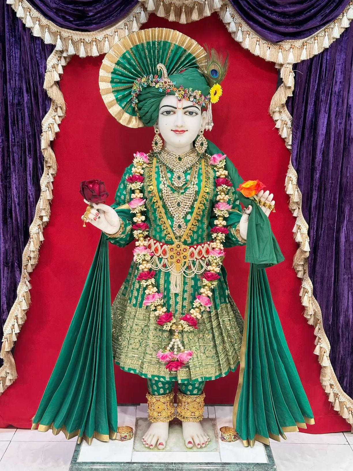 Swaminarayan idol with floral offerings.