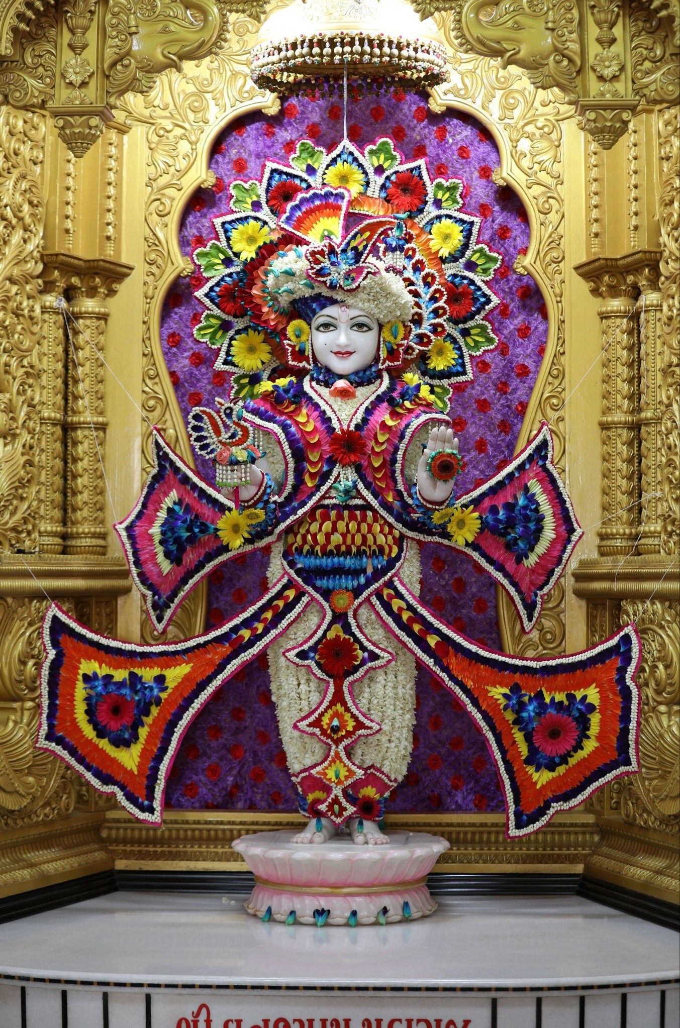 Swaminarayan deity adorned with flowers.