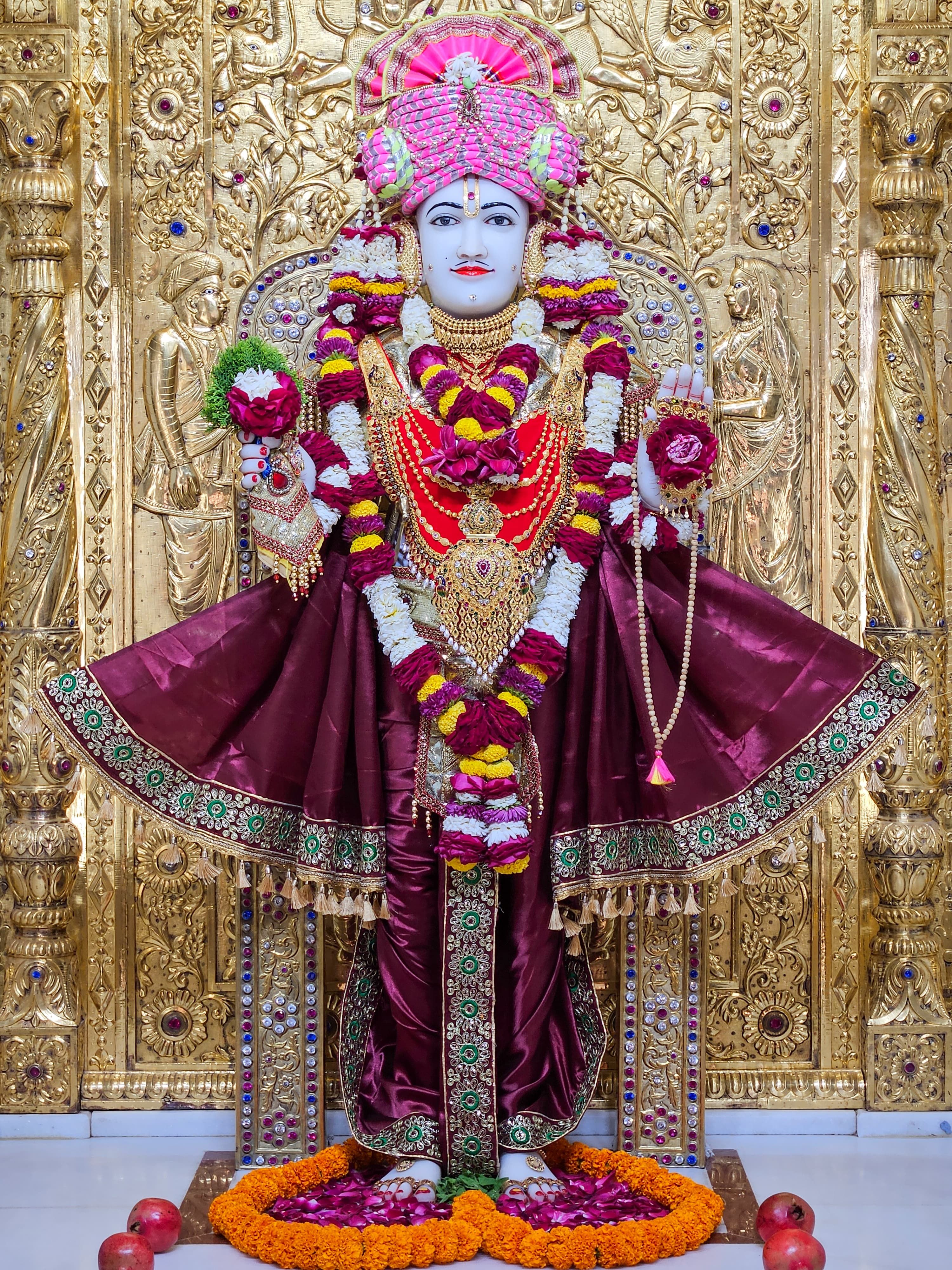 Golden Swaminarayan deity adorned with flowers