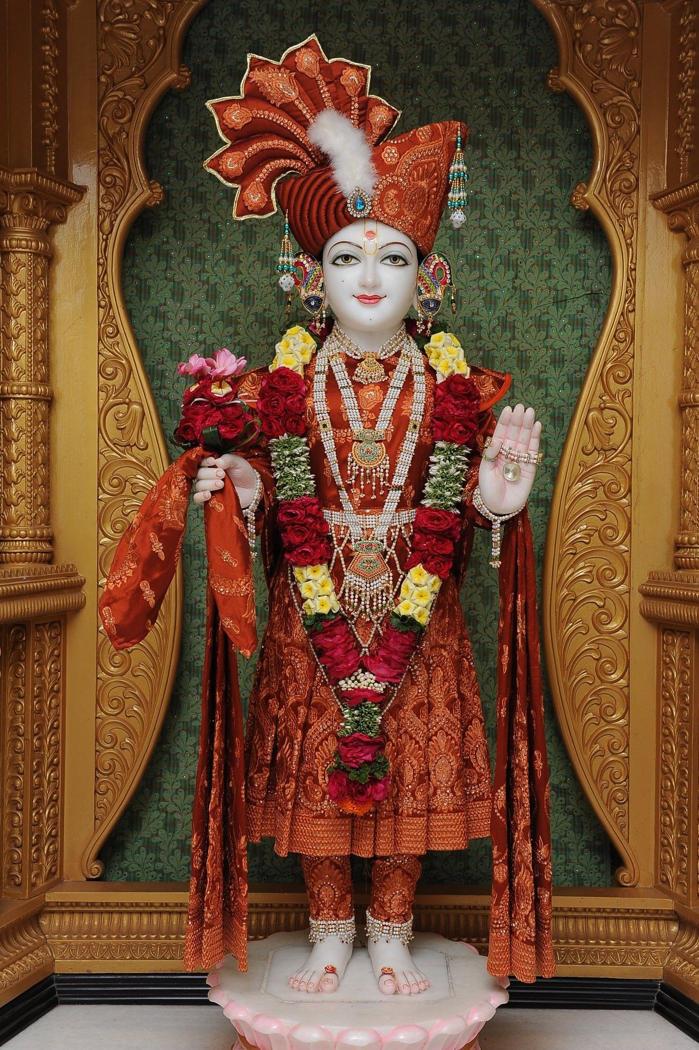 Swaminarayan murti adorned with flowers.