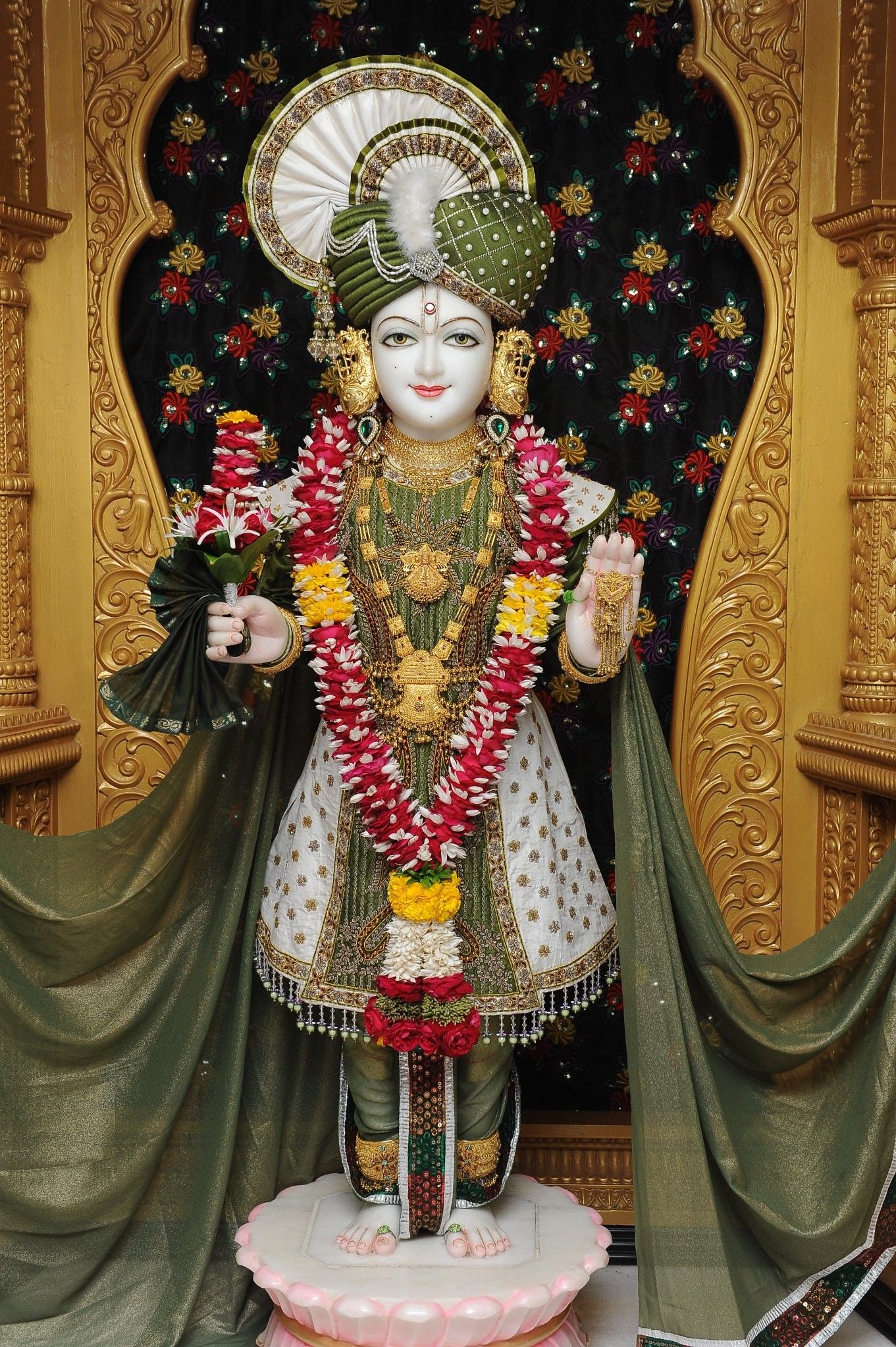 Swaminarayan statue adorned with flowers.