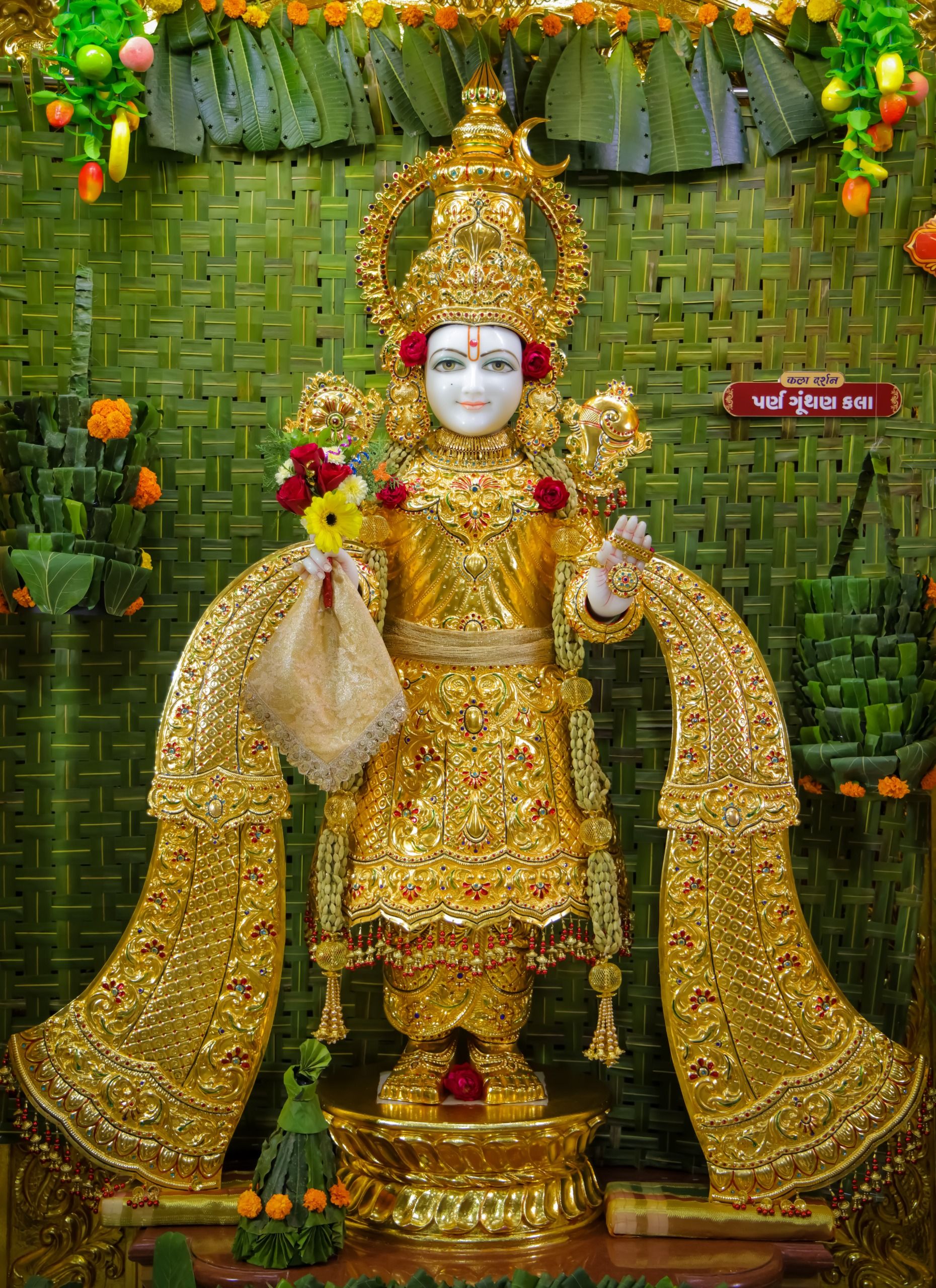 Golden Swaminarayan idol adorned with flowers