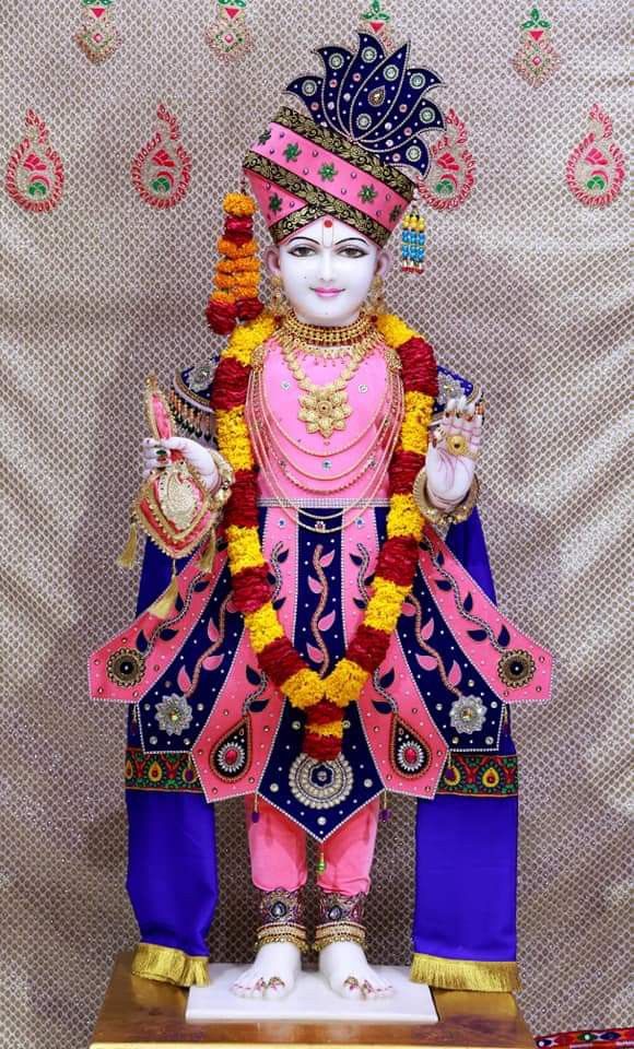 Ornate Swaminarayan statue with floral garland