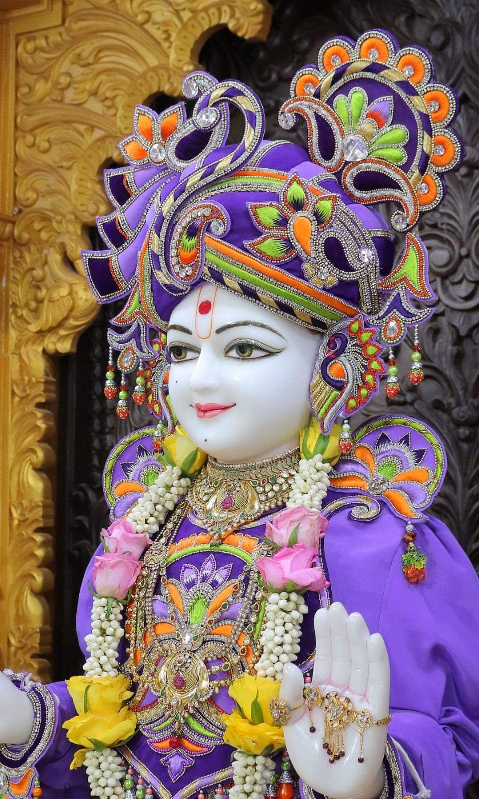 Swaminarayan murti adorned with flowers.