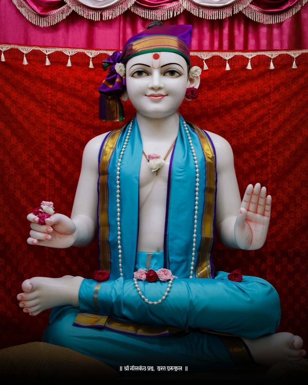 Marble statue of Swaminarayan in blessing pose.