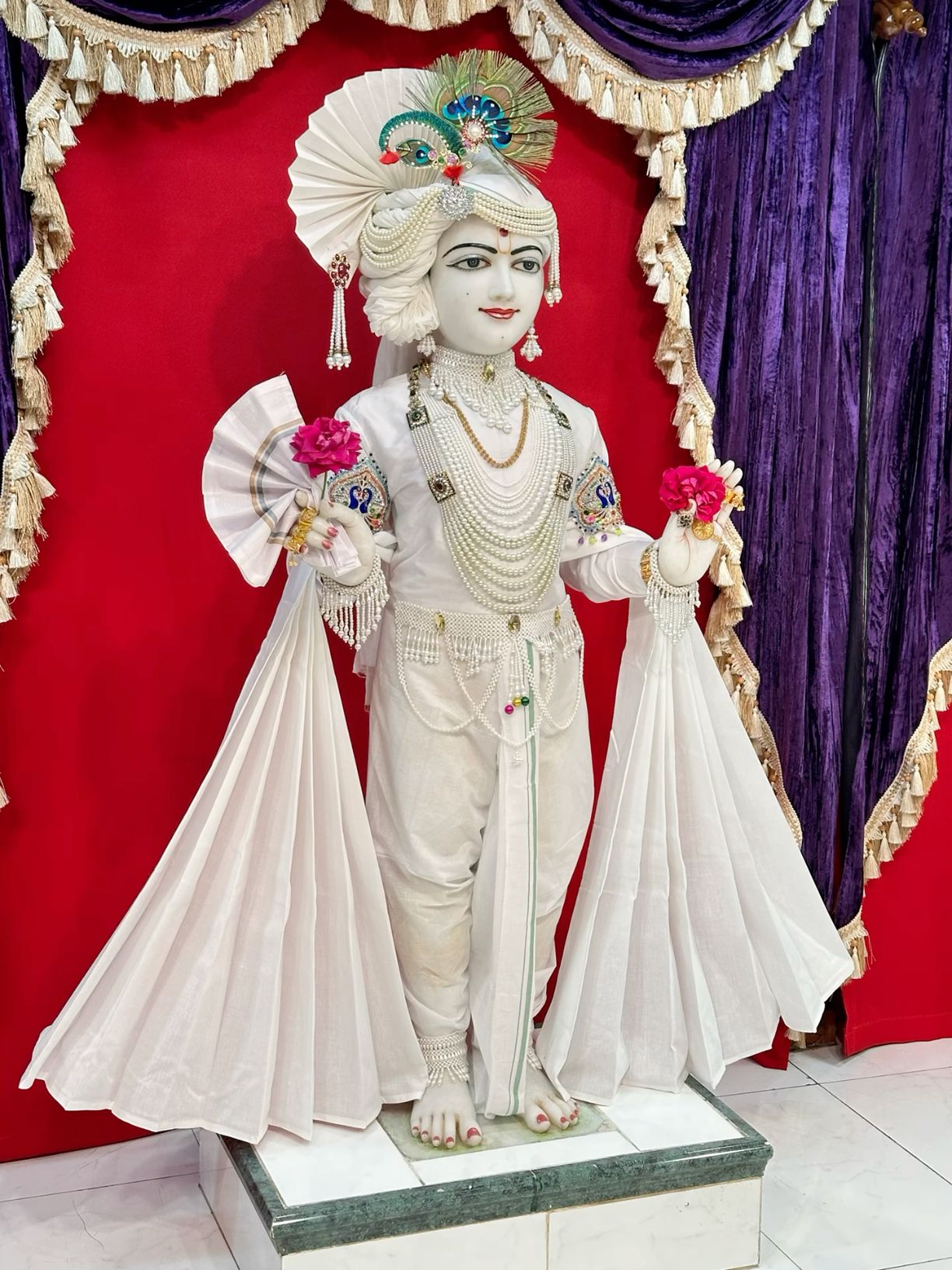 Swaminarayan deity statue adorned with pearls.