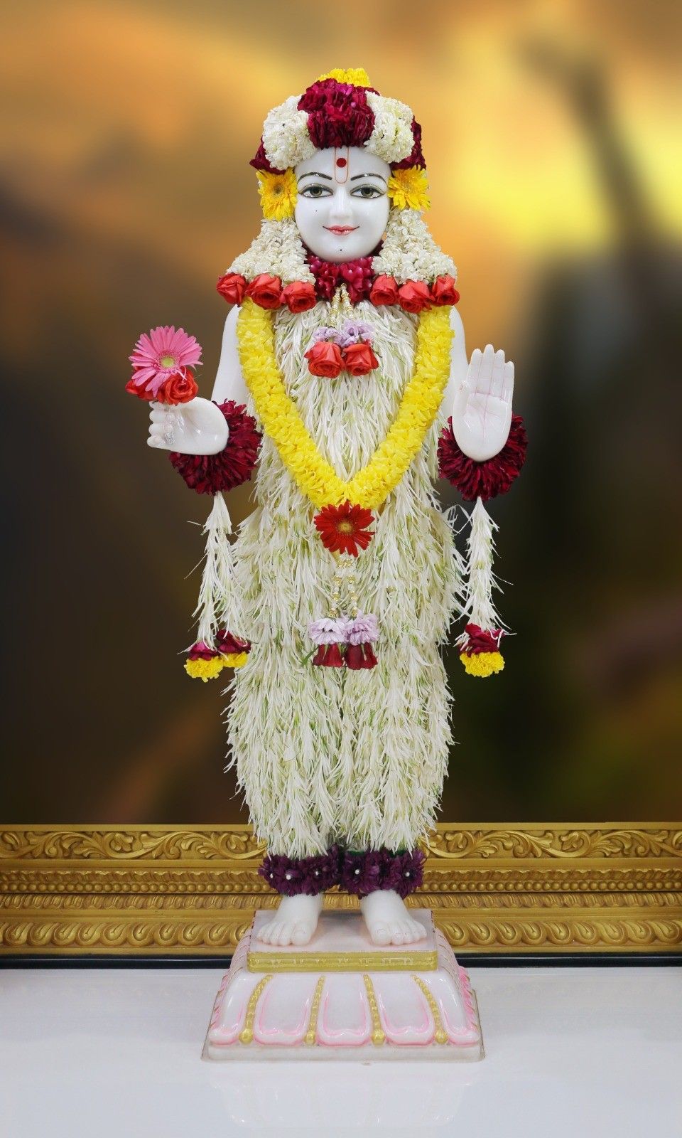 Swaminarayan deity with floral decorations.