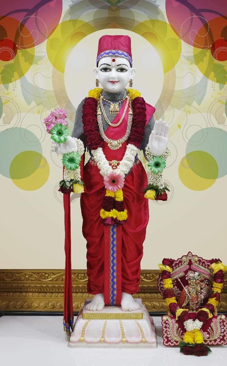 Swaminarayan statue adorned with flowers.