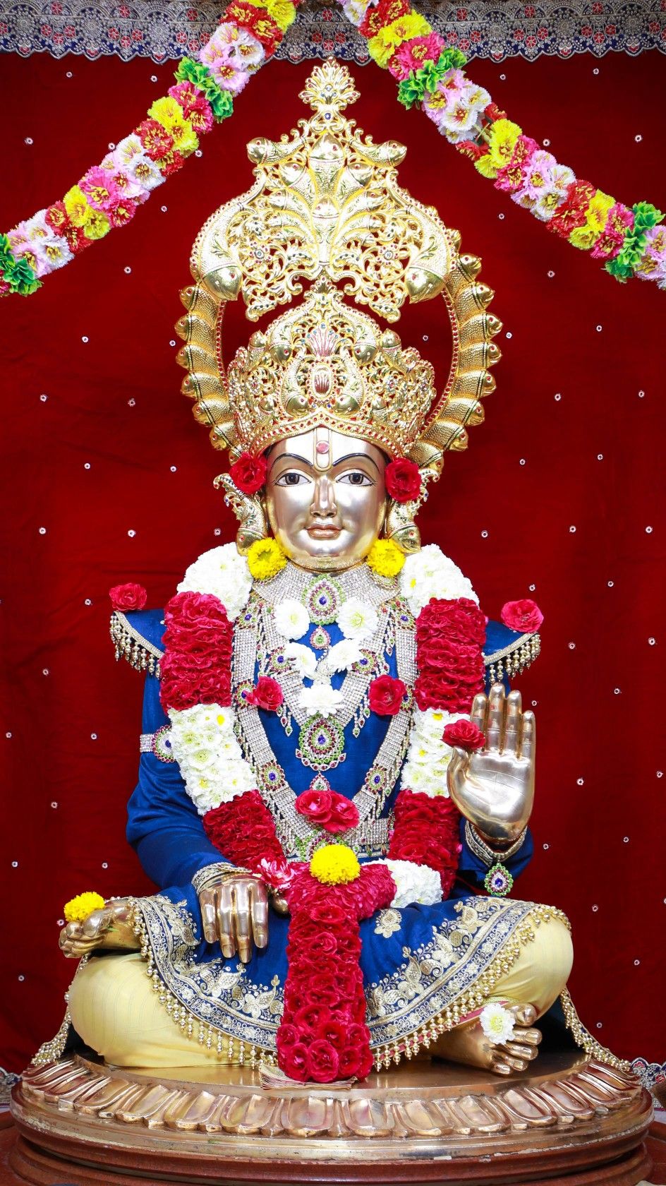 Swaminarayan statue adorned with flowers.